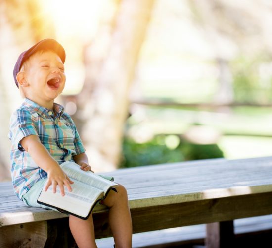 boy sitting on bench while holding a book